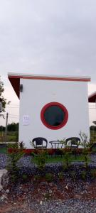 een wit gebouw met een rood raam en twee stoelen bij จันทร์ทิพย์คคำชะโนด 2 เฟท 2 in Ban Dung