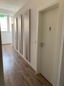 an empty hallway with white walls and wooden floors at Hostel Terre in Fellbach +1 photo