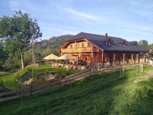 a large wooden house on a green field at Penzion Farma Žleby in České Žleby