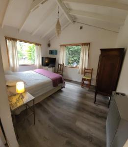 Un dormitorio con una cama y una mesa y dos ventanas. en Casas La Violeta, en Villa La Angostura