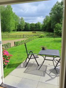 a patio with a table and a bench and a field at Halte Liempde Logies in Liempde