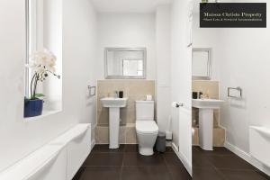 a white bathroom with two sinks and a toilet at Dollis Valley 3Bedroom House Sleeps 8 in London With FREE PARKING By Maison Christo Property Short Lets & Serviced Accommodation in Barnet +33 photos