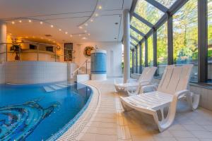 a swimming pool with two white chairs in a house at Malachit Karpacz SPA Hotel in Karpacz