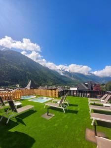 a row of lounge chairs on a lawn with mountains in the background at Park Hotel Suisse & Spa in Chamonix-Mont-Blanc