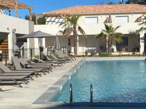 ein Pool mit Stühlen und Sonnenschirmen neben einem Haus in der Unterkunft Superbe appartement vue mer terrasse couverte face à la mer in Linguizzetta