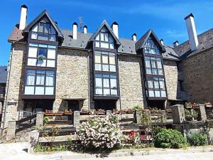 un gran edificio de ladrillo con ventanas en blanco y negro en Peña Telera Petfriendly - Arafita Apartamentos, en El Pueyo de Jaca