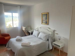 a white bedroom with a bed and a table at Apartamento El Mirador de Sierra Mágina Noalejo entre Granada y Jaén in Noalejo +74 photos