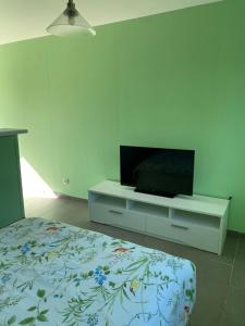 马雷讷Au lilas des Indes的卧室里有一张床和一台放在梳妆台上的电视