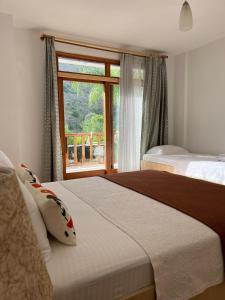 a bedroom with two beds and a large window at Yonca Hotel in Adrasan