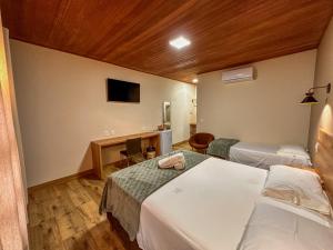 a hotel room with two beds and a television at Pousada Casa Zanotto in Pirenópolis