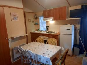 Il comprend une cuisine équipée d'une table avec des chaises et d'un réfrigérateur blanc. dans l'établissement Mobil Home Confort G 07, à Saint-Georges-de-Didonne