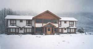 une grande maison avec de la neige sur le devant dans l'établissement Complejo Turístico Sol de Puelo, à Lago Puelo