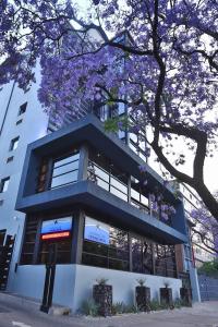 um edifício com uma árvore florida à sua frente em Inani Hotel Morning Star em Pretoria