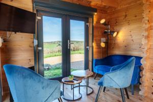 a room with blue chairs and a large window at Le Chalet du Crescent in Saint-Germain-des-Champs