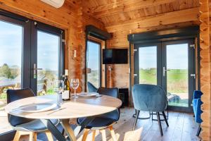 a dining room with a table and chairs and windows at Le Chalet du Crescent in Saint-Germain-des-Champs