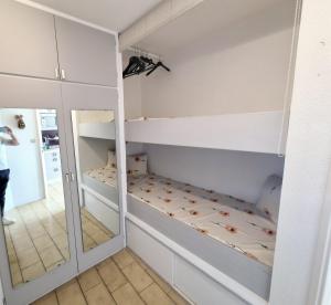 Cette chambre comprend des lits superposés et un miroir. dans l'établissement Studio cabine moderne design avec vu sur jardin , piscine, à La Grande Motte 15 autres photos
