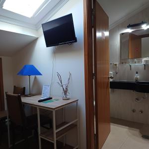 a room with a desk with a tv on the wall at Residencialusobrasileira in Leça da Palmeira
