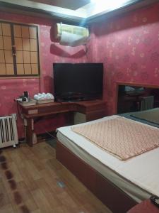 a bedroom with a tv and a bed and a desk at City Park Motel in Seongnam