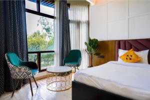 ein Schlafzimmer mit einem Bett und zwei Stühlen und einem Fenster in der Unterkunft Hide-In Hostel Delhi in Neu-Delhi