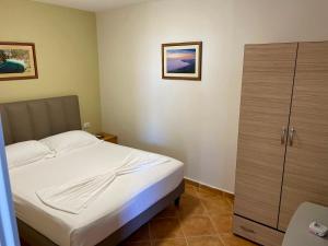 a small bedroom with a bed and a cabinet at Chalet Ambel in Dhërmi