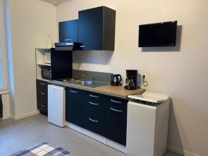 a kitchen with blue cabinets and a white refrigerator at Charmant Studio meublé 349 in Vittel