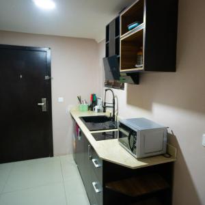 a small kitchen with a sink and a microwave at The Lodge-Stack By Kabachi in Lagos