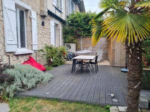 eine Terrasse mit einem Tisch und einer Palme in der Unterkunft Artist house with piano and charming garden in Reims