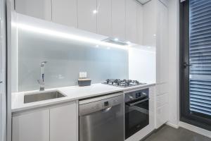 a white kitchen with a sink and a stove at Exquisite And Warm 1br Nest In Footscray Pool Gym in Melbourne