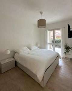 a white bedroom with a large bed and a window at Sweet Serenity Apartment in Palau