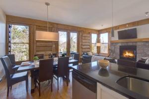 a kitchen and living room with a table and a fireplace at Luxurious Scandinavian Cottage with Private Jacuzzi in Lac-Superieur