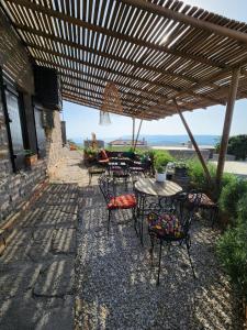 a patio with tables and chairs under a wooden pergola at Assos Sunset Hotel in Behramkale