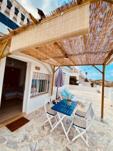 d'une terrasse avec une table et des chaises sous un parasol de paille. dans l'établissement La Juanita - Dosel, à Faro de Cullera