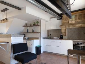a kitchen with white cabinets and a black chair at La Guinda Real- Centro histórico in Vigo