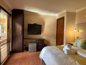 a hotel room with a bed and a flat screen tv at Accommodation Bedfordview - Hethersett Guesthouse in Johannesburg