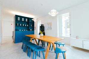 a dining room with a wooden table and blue chairs at Surf & Sea Suites in Parede