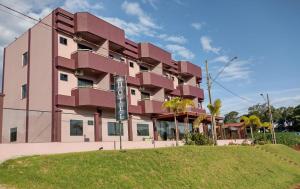 a pink building with a sign in front of it at Conforto Plaza Hotel in Capitão Leônidas Marques