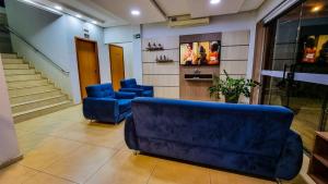 a living room with a couch and two blue chairs at Conforto Plaza Hotel in Capitão Leônidas Marques