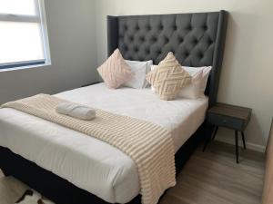 a bedroom with a large bed with white sheets and pillows at Monty Cosy Haven in Cape Town
