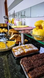 a buffet filled with different types of cakes and pastries at Conforto Plaza Hotel in Capitão Leônidas Marques