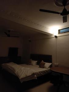 a bed in a dark room with a ceiling fan at Shanti Sadan Homestay in Rājgarh +5 photos