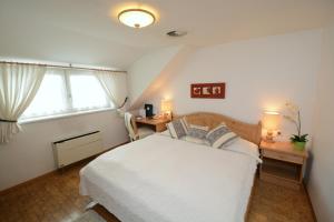 a bedroom with a white bed and a window at Hotel & Restaurant Braunstein - Pauli´s Stuben in Purbach am Neusiedlersee