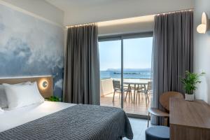 a hotel room with a bed and a view of the ocean at Blue Dome Hotel in Platanias