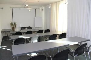 einen Konferenzraum mit Tischen, Stühlen und einem Whiteboard in der Unterkunft Hotel am Hirschgarten in Filderstadt