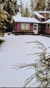 Una casa con nieve en el suelo delante de ella. en Casas La Violeta, en Villa La Angostura