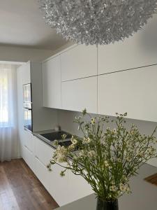 a kitchen with white cabinets and a vase with flowers at Apartman My Choice in Bihać