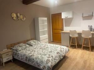 a bedroom with a bed and a kitchen with two stools at La nuit étoilée in Rocroi
