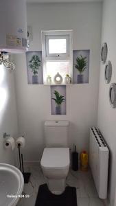 a bathroom with a toilet and a window with potted plants at Newly built home away from home in Peterborough
