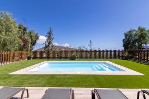 a swimming pool in a yard with chairs and a fence at VV Finca El Toscalito in Arona