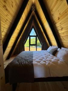 Una cama en una habitación de madera con ventana. en Lettaşi Bungalov, en Rize