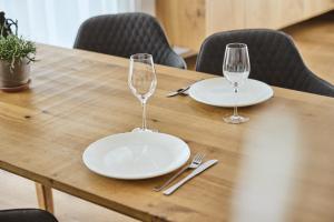 a wooden table with two empty plates and wine glasses at Stilvolles, lichtdurchflutetes Luxus-Appartement in der Residenz Silvretta - Inklusive Silvretta Card Premium in See